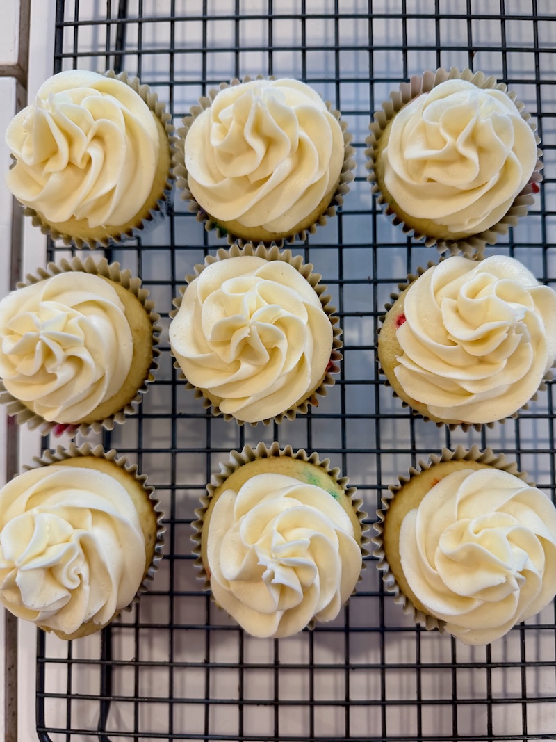 Vanilla cupcakes with rainbow sprinkles inside and vanilla buttercream on top
