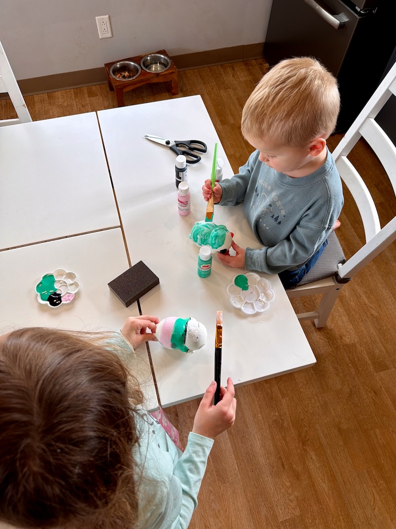 Kids sitting at kitchen table painting squishy toys