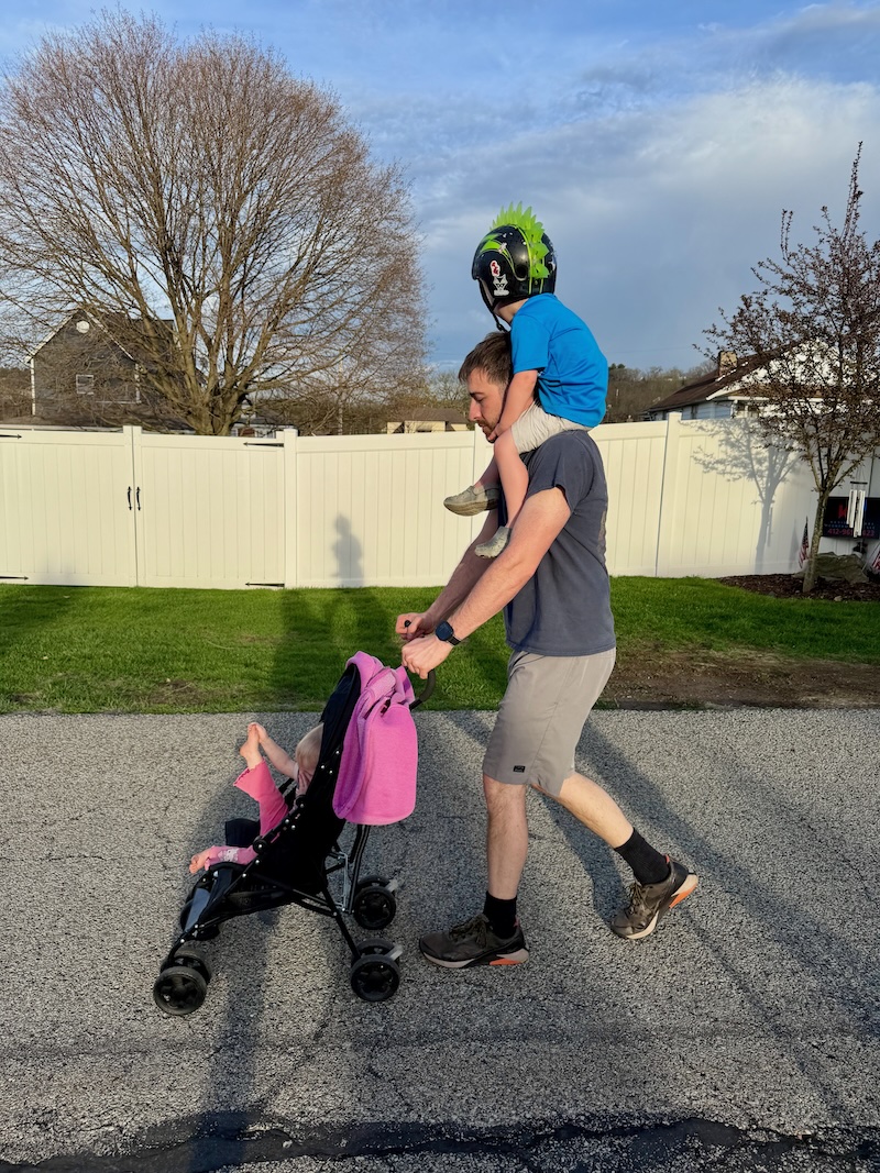 Dad with son on his shoulders while he pushes stroller
