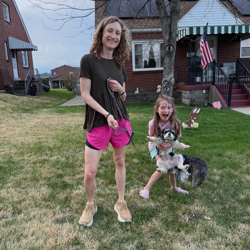 Mom and daughter standing in yard with small dogs on leashes