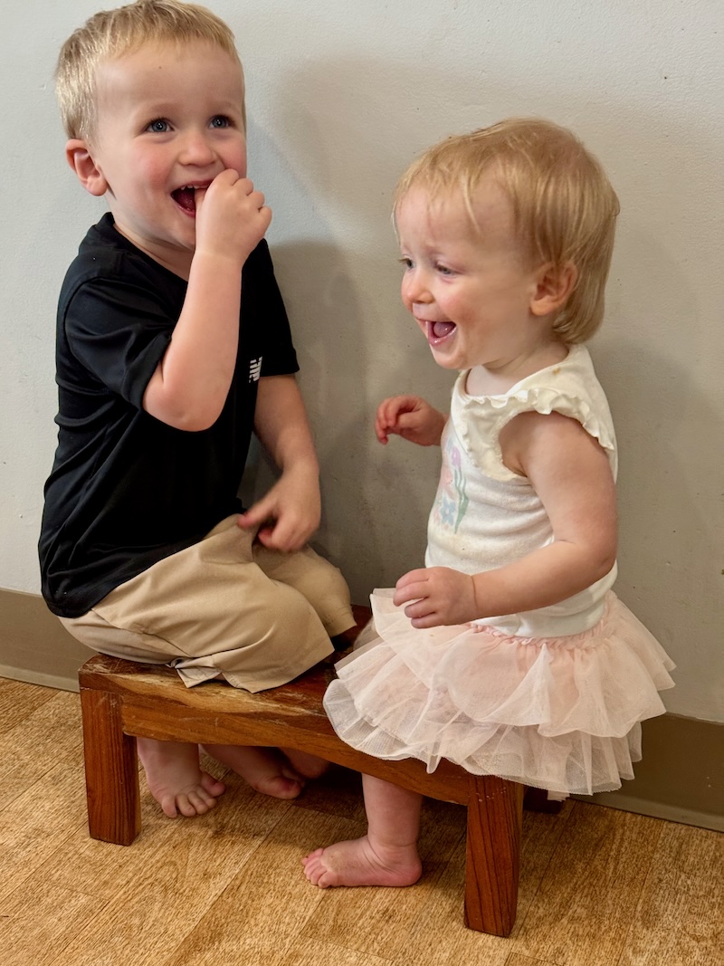 Toddler boy and girl sitting in dog dish