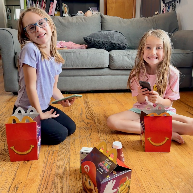 Girls sitting on floor with Happy Meals from McDonalds