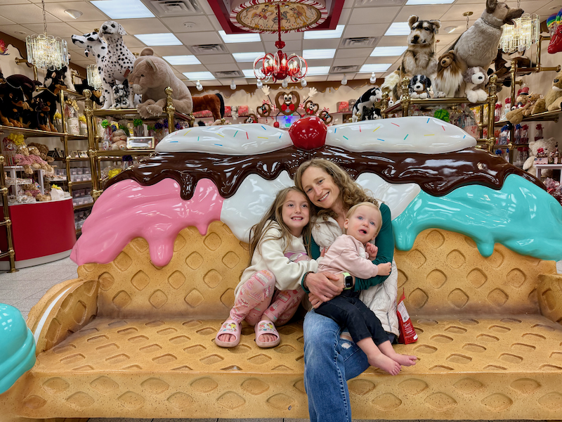 Mom and daughters sitting on novelty bench in Sarris Candies