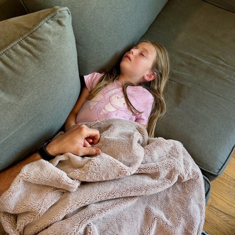 Girl sleeping under blanket on couch
