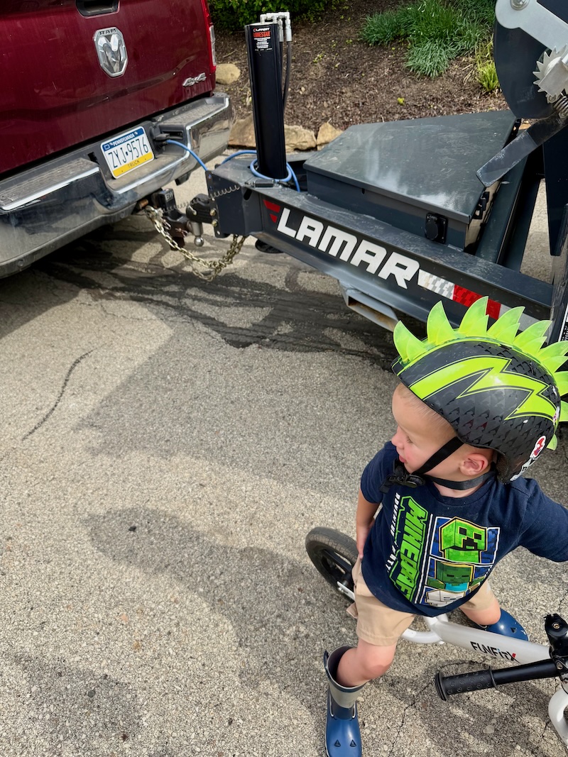 Toddler boy on bike by truck