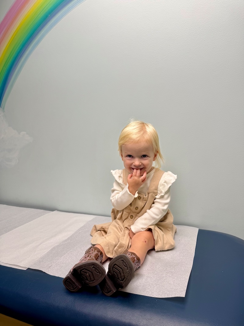 Toddler girl sitting on table at doctor's office