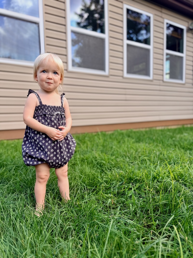 18 month old toddler girl standing in grass