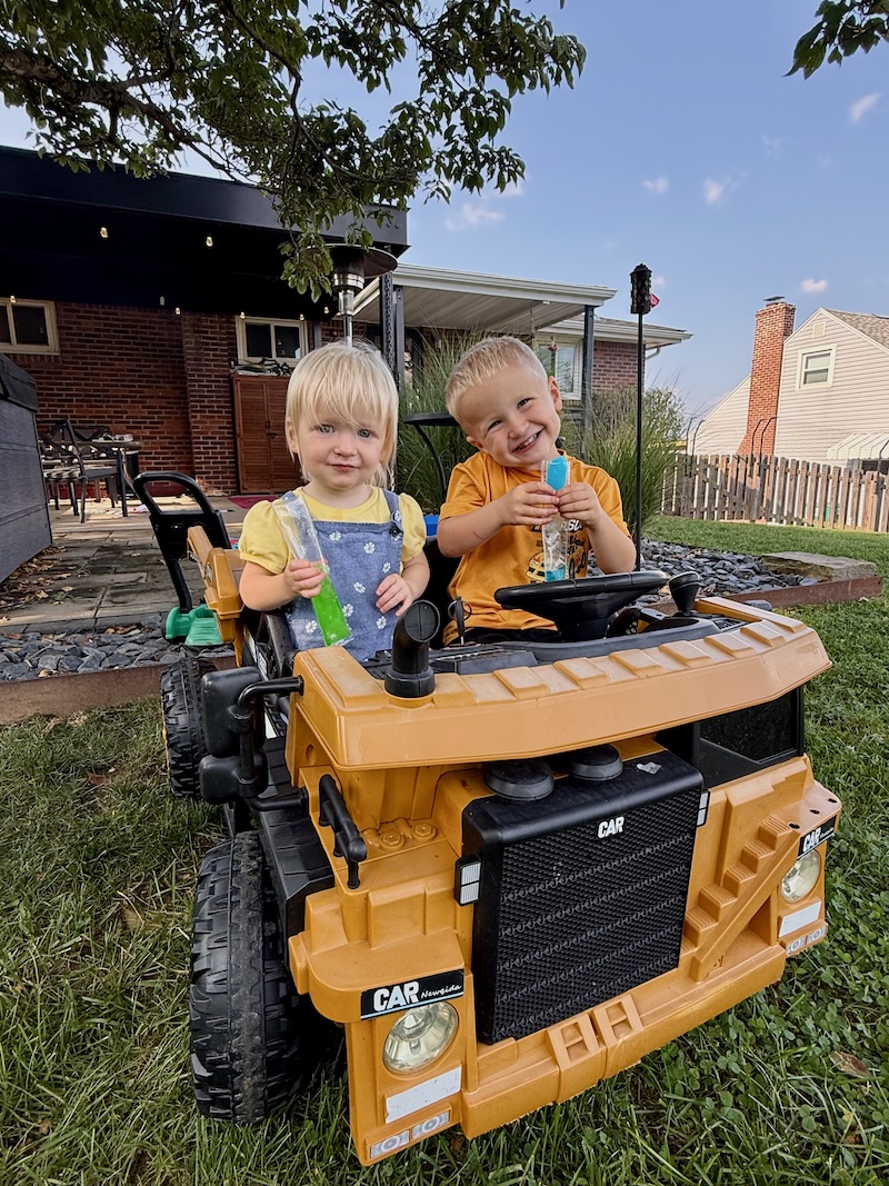 Toddlers eating popsicle while riding in power wheel dump truck