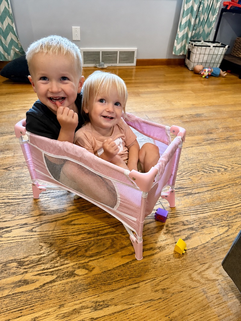Brother and sister sitting in baby doll crib