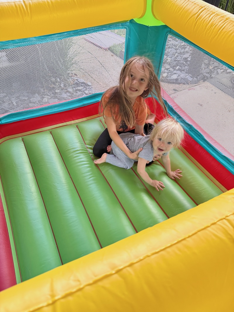 Girl and toddler girl playing in bounce house