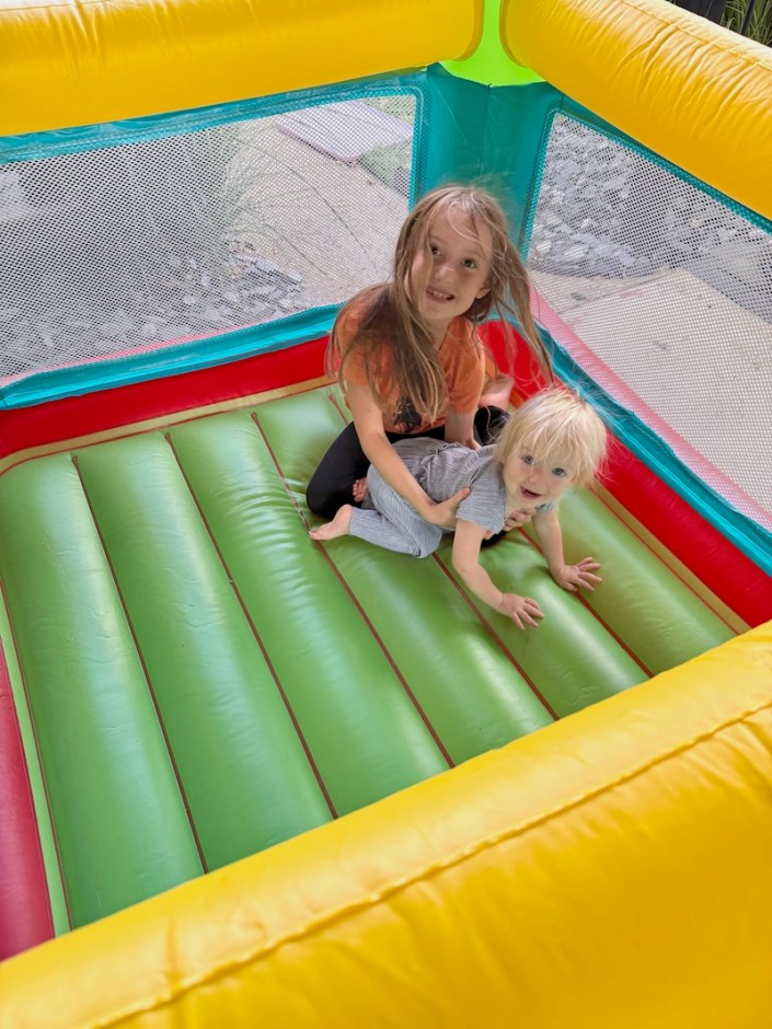 Girl and toddler girl playing in bounce house