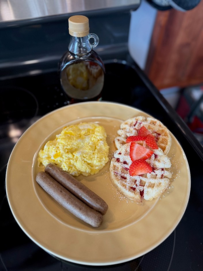 Waffles, sausage, and eggs with maple syrup