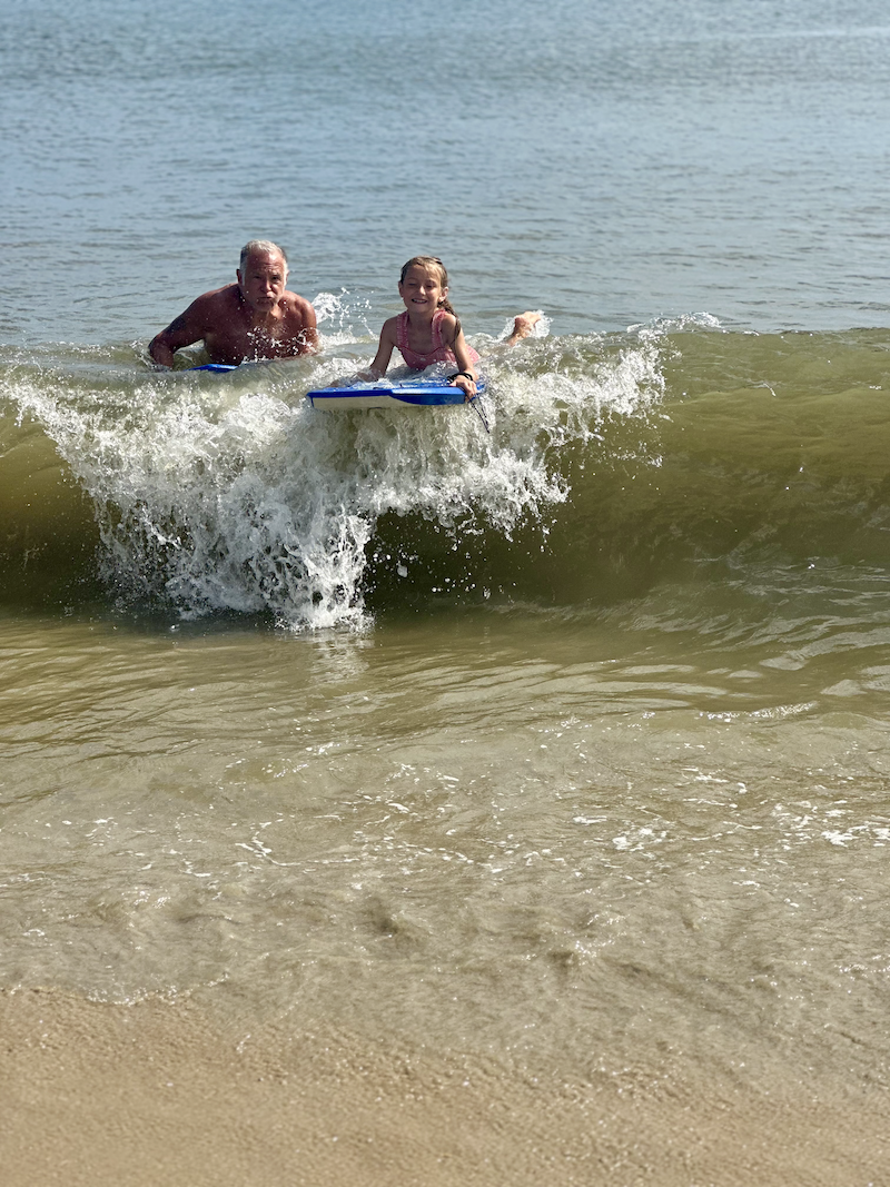 Grandpa and granddaughter boogie boarding in Atlantic ocean