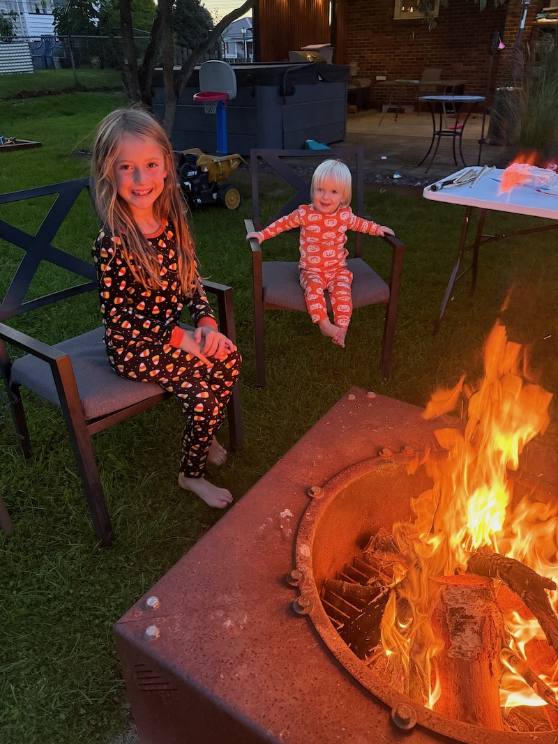 Girl and sister sitting by bonfire
